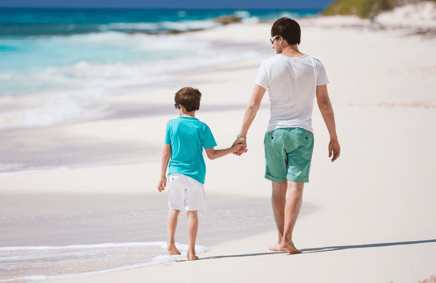 Father holding his son and walking on the beach 